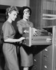 Two female office workers arranging files in filing cabinet Poster Print - Item # VARSAL25548408