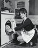 Portrait of a young woman putting clothes into a dryer Poster Print - Item # VARSAL25541877