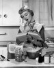 Young woman reading a cookbook in a domestic kitchen Poster Print - Item # VARSAL2555847B
