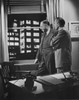 Two businessmen in office looking through window  1950s Poster Print - Item # VARSAL25515349