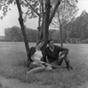 Young couple sitting under tree Poster Print