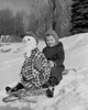 Boy sledding down snowy hill with snowman on sled Poster Print - Item # VARSAL255422730