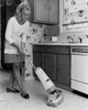 Young woman using vacuum cleaner in kitchen Poster Print - Item # VARSAL2555138