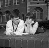 Young couple reading on grass outside university Poster Print - Item # VARSAL255418381