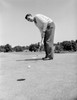 Young golfer putting golf ball into hole Poster Print - Item # VARSAL255419223