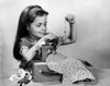Girl sewing clothes with a toy sewing machine Poster Print - Item # VARSAL25513896