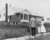 Rear view of a mid adult couple standing with their two children in front of a house Poster Print - Item # VARSAL25517118