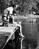 Side profile of a boy with his father sitting on a pier and fishing in a lake Poster Print - Item # VARSAL25519667