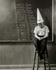 Boy wearing a dunce cap sitting in front of a blackboard Poster Print - Item # VARSAL2553265