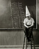 Boy wearing a dunce cap sitting in front of a blackboard Poster Print - Item # VARSAL2553265