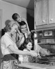 Side profile of a mid adult woman putting a turkey into an oven with her family standing beside her Poster Print - Item # VARSAL25535505