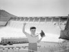 Portrait of boy holding camera  dam in the background Poster Print - Item # VARSAL255419365