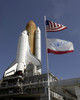 At the Kennedy Space Center in Florida, flags swing in the breeze as space shuttle Endeavour approaches Launch Pad 39A. Poster Print - Item # VARPSTSTK202755S