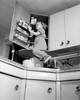 Girl standing on kitchen worktop  looking in cupboard Poster Print - Item # VARSAL25514360