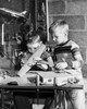 Boy making a model airplane with another boy looking at him Poster Print