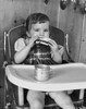 Baby girl sitting in a high chair and eating a slice of bread Poster Print - Item # VARSAL2559713