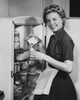 Portrait of a young woman standing in front of a refrigerator pouring milk into a glass Poster Print - Item # VARSAL2552508