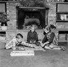 Girl and two boys playing monopoly in front of fireplace Poster Print - Item # VARSAL255418597