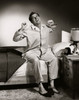 Mid adult man sitting on the edge of the bed stretching Poster Print - Item # VARSAL2553047