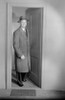 Mid adult man wearing overcoat and hat emerging from door Poster Print - Item # VARSAL255418886