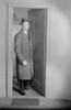 Mid adult man wearing overcoat and hat emerging from door Poster Print - Item # VARSAL255418886