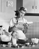 Young woman reading a cookbook in a domestic kitchen Poster Print - Item # VARSAL2554585A