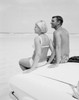Couple in swimwear sitting on hood of car on beach Poster Print - Item # VARSAL255422423
