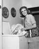 Portrait of young woman taking clothes out of washing machine Poster Print - Item # VARSAL2555140