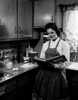 Young woman reading recipe book in kitchen Poster Print - Item # VARSAL25536221
