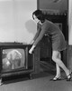 Side profile of a young woman changing channels of a television Poster Print - Item # VARSAL2551232