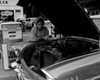 Mature woman leaning against car and looking  at car engine Poster Print - Item # VARSAL255416696