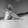 Young woman sitting on beach and applying suntan lotion Poster Print - Item # VARSAL255418010