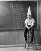 Boy wearing a dunce cap sitting in front of a blackboard Poster Print - Item # VARSAL2553265A