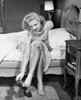 Young woman sitting on bed removing shoes Poster Print - Item # VARSAL2557564