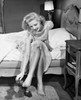 Young woman sitting on bed removing shoes Poster Print - Item # VARSAL2557564