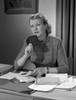 Woman sitting at desk holding booklet Poster Print - Item # VARSAL25527459