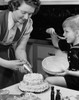 Mid adult woman preparing a cake with her son sitting beside her Poster Print - Item # VARSAL25536209