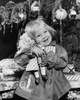 Close-up of a girl standing in front of Christmas presents and hugging a doll Poster Print - Item # VARSAL25522173