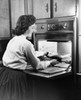 Young woman putting food into an oven Poster Print - Item # VARSAL25512420