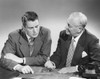 Two businessmen discussing a blueprint in an office Poster Print - Item # VARSAL25523109