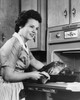 Young woman putting a turkey into an oven Poster Print - Item # VARSAL2555135