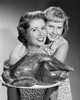 Mid adult woman holding roasted turkey on a tray with her daughter hugging her from behind Poster Print - Item # VARSAL25519579A