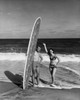 Young man holding surfboard on beach with young woman standing beside him Poster Print - Item # VARSAL255335