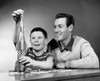 Boy playing with a model rocket with his father beside him Poster Print - Item # VARSAL25519658C
