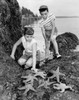 Girl and her brother looking at starfish on a rock Poster Print - Item # VARSAL25516730