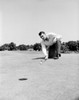 Young golfer putting golf ball into hole Poster Print - Item # VARSAL255419221