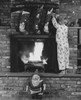 Rear view of boy standing on fireplace and grabbing Christmas stocking Poster Print - Item # VARSAL25525146