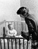 Mother standing at crying baby boy sitting in crib Poster Print - Item # VARSAL2556003