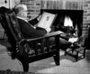 Man looking at old photograph by fireplace Poster Print - Item # VARSAL25549013