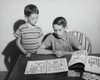 Two children looking at a collection of postage stamps Poster Print - Item # VARSAL25516410
